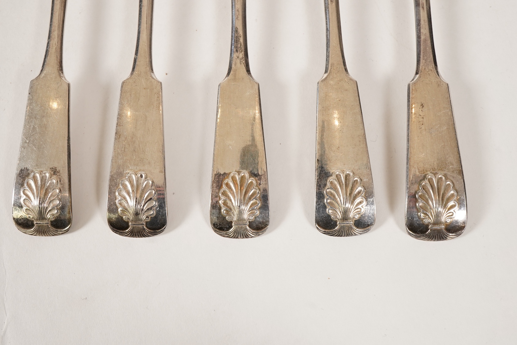 A set of twelve white metal fiddle and shell pattern table forks and five matching dessert forks